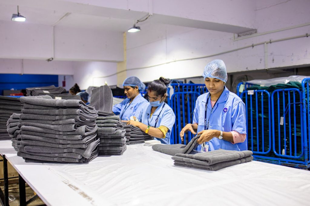 Workers in a textile factory carefully folding fabrics, highlighting industrial work environments.