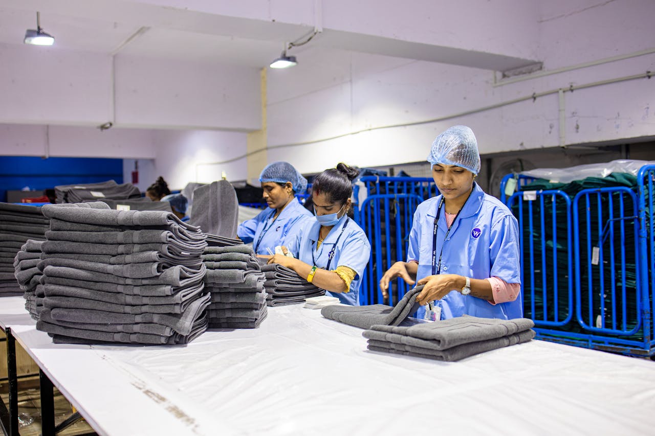 Workers in a textile factory carefully folding fabrics, highlighting industrial work environments.